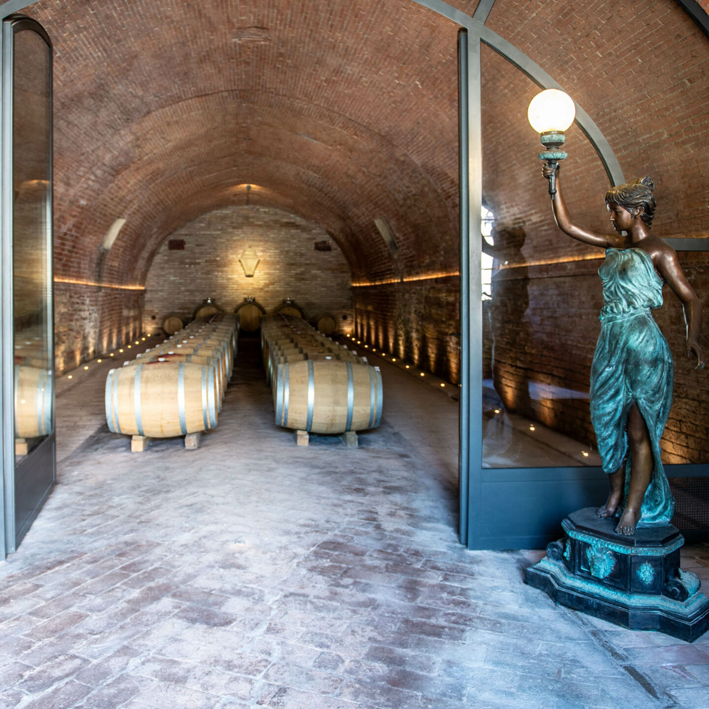 Entrance to the underground cellar of Cantina Villa Cosmiana with wine barrels and a statue