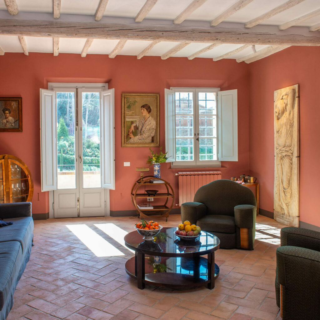 Text: Cozy living room of Cantina Villa Cosmiana with red walls and comfortable furnishings