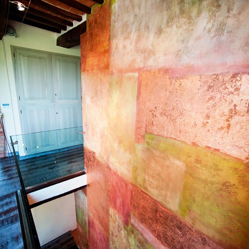 Colorful abstract wall design in a modern hallway with wooden beam ceiling, glass railing, and recessed lighting, designed by Archidomus, Architect Monica Rossi.