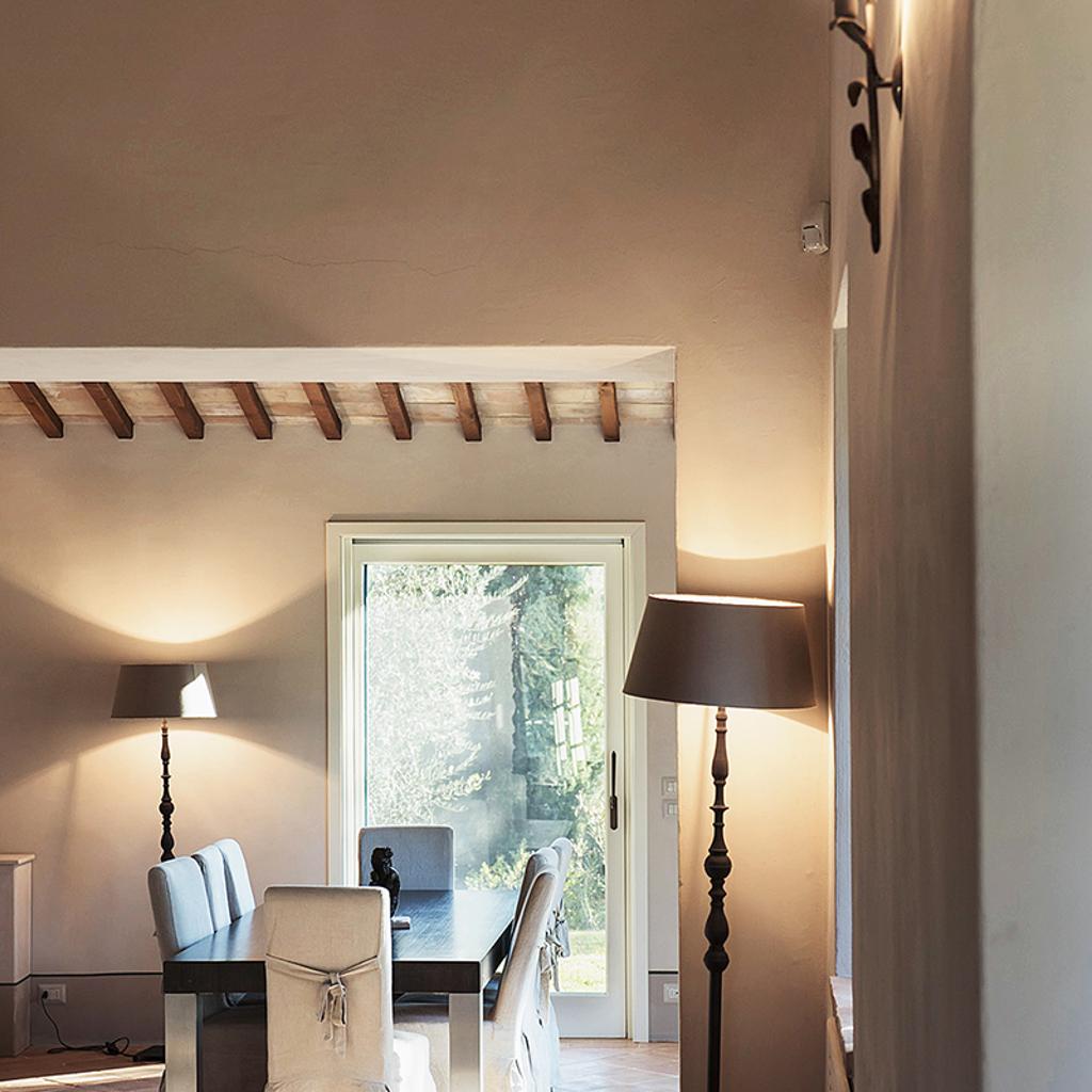 Dining room with wooden ceiling beams, a large window, and elegant furnishings, designed by Archidomus - Architect Monica Rossi.