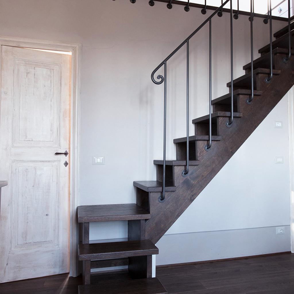 Modern staircase with dark wood steps and wrought iron railing, designed by Archidomus - Architect Monica Rossi.