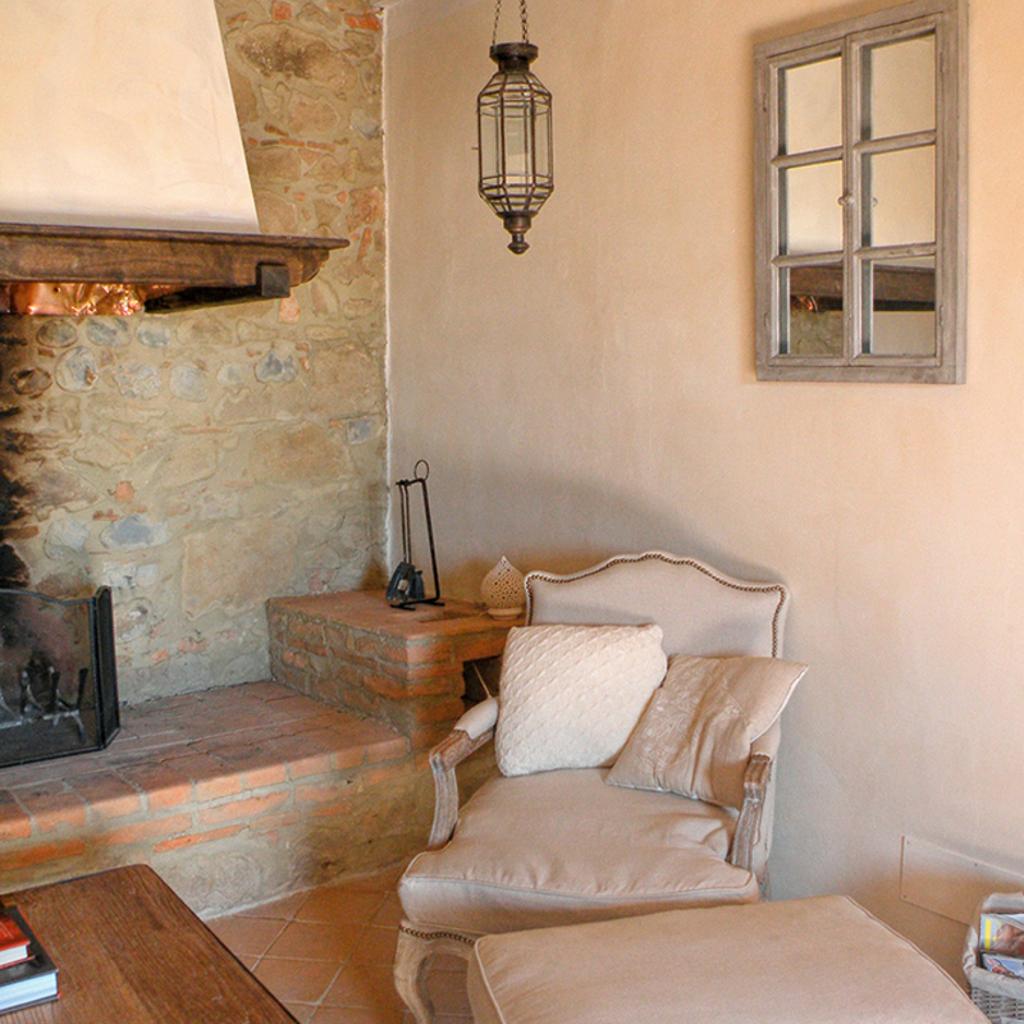 Cozy corner with stone fireplace, armchair, and decorations, designed by Archidomus - Architect Monica Rossi.