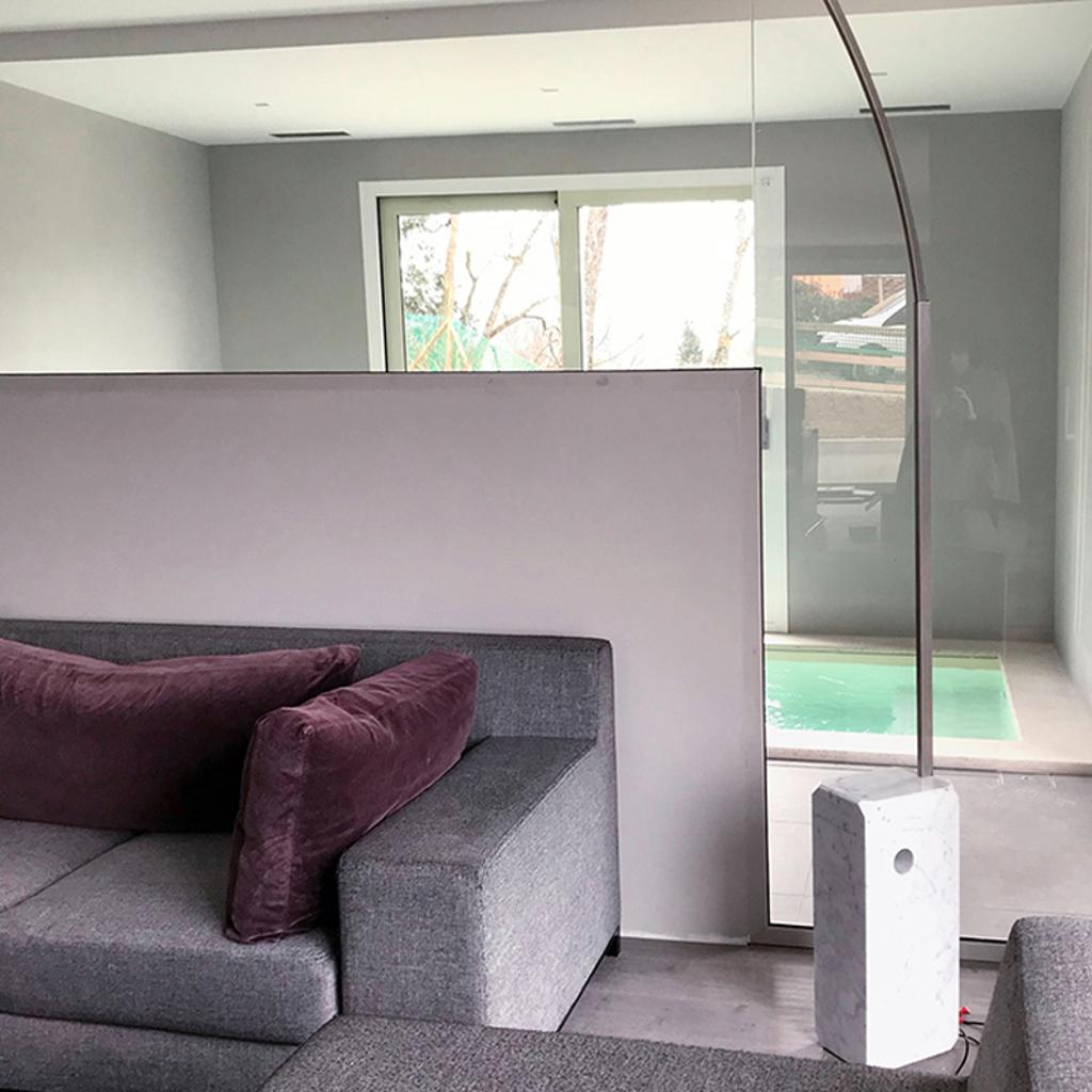 Modern living room with a gray sofa and purple pillows, featuring a large window overlooking an indoor pool, designed by Archidomus - Architect Monica Rossi.