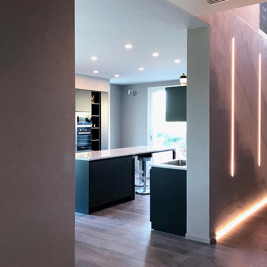 Cucina moderna con mobili neri eleganti, una grande isola e illuminazione minimalista, realizzata da Archidomus - Architetto Monica Rossi.