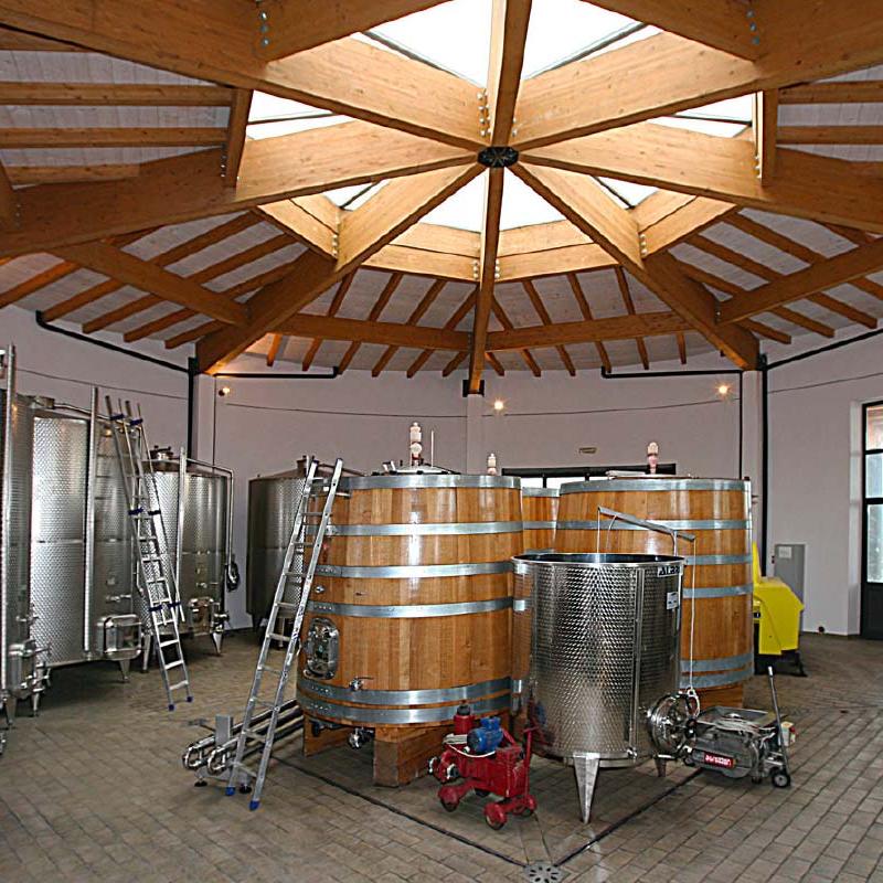 Steel and wooden wine tanks in a cellar with a wooden ceiling, designed by Archidomus - architect Monica Rossi