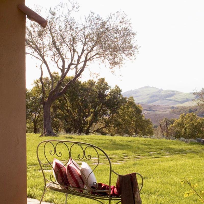 Wrought iron bench with cushions on a green lawn designed by Archidomus - Monica Rossi architect