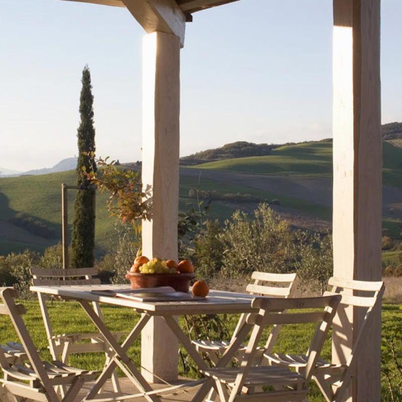 Outdoor dining table with wooden chairs and a view of the hills, house designed by Archidomus - Monica Rossi architect