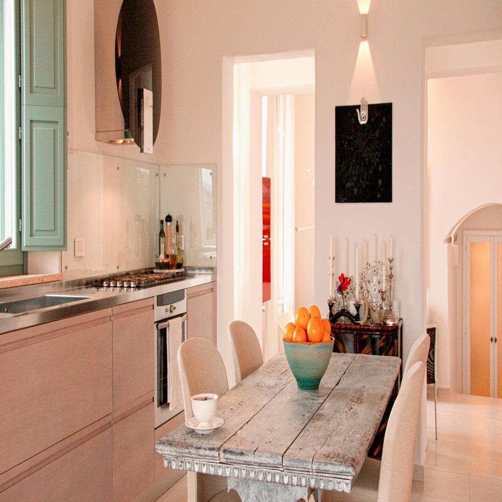 Modern kitchen designed by Archidomus, featuring a rustic dining table with a bowl of oranges and minimalist decor by Architetto Monica Rossi.