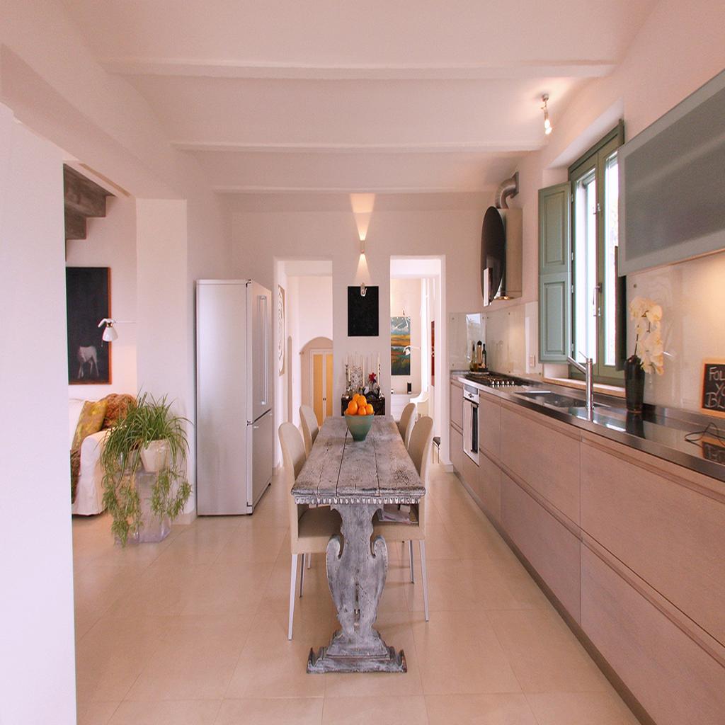 Modern kitchen and living area designed by Archidomus, featuring a rustic dining table with a bowl of oranges and minimalist decor by Architetto Monica Rossi.