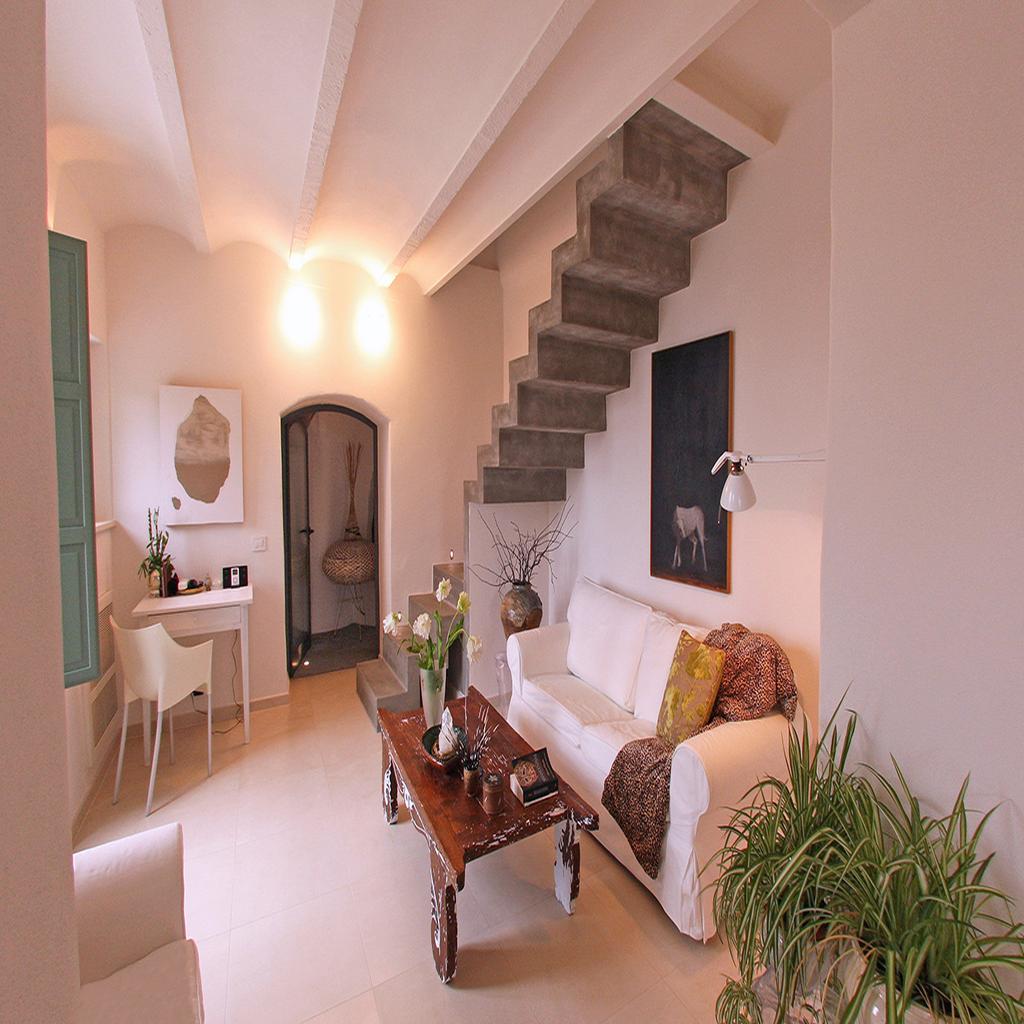 Modern living room designed by Archidomus, featuring white sofas, a wooden coffee table, and a minimalist staircase by Architetto Monica Rossi.