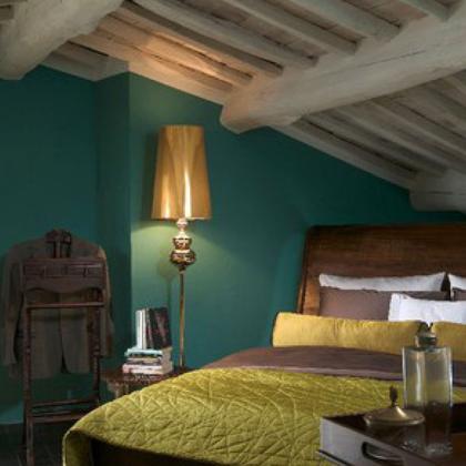 Bedroom with wooden bed, green walls, and gold lamp