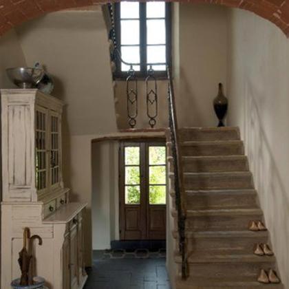 Entrance with stone staircase, antique cabinet, and brick arch