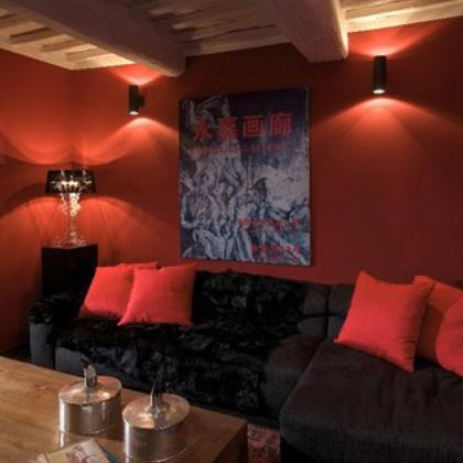 Living room with red walls, black sofa, and red cushions